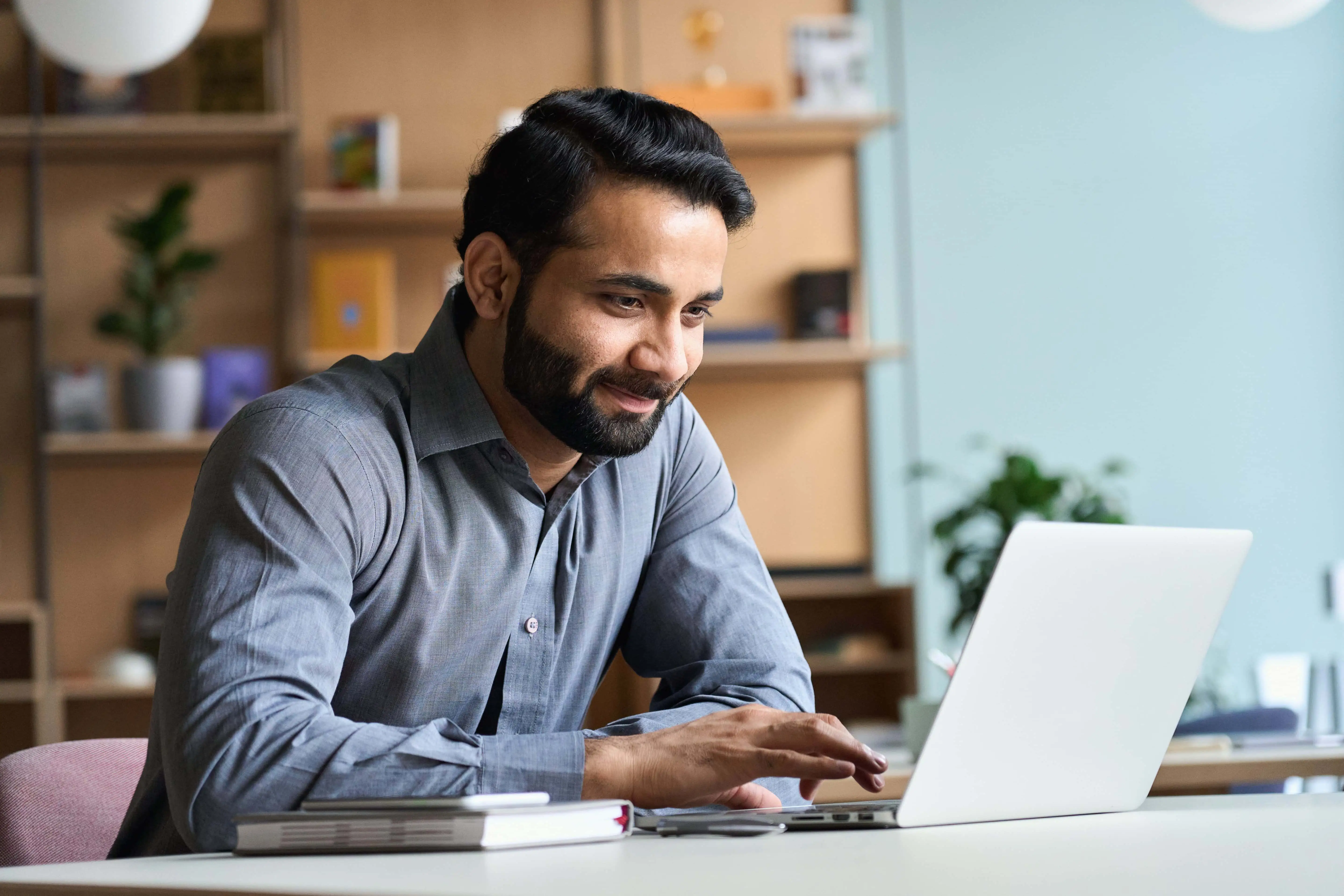 a man sit and smiling in front of laptop